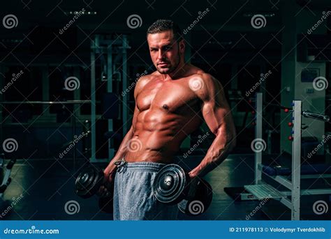Bodybuilder In Gym Training And Workouts Dumbbells Exercises Sportsman With Naked Torso