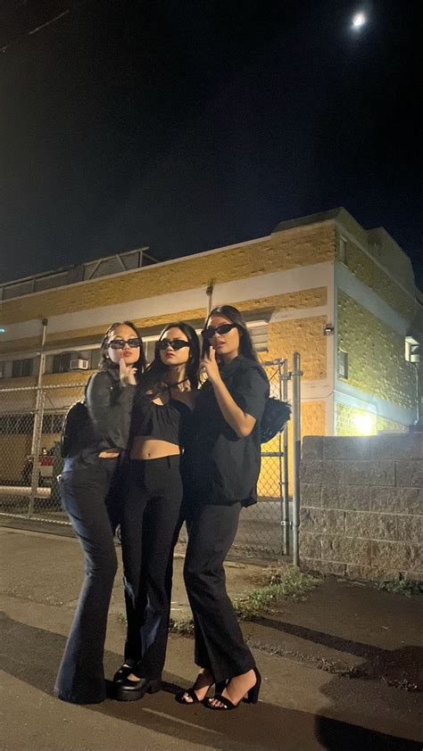 Three Women Standing Next To Each Other In Front Of A Building At Night