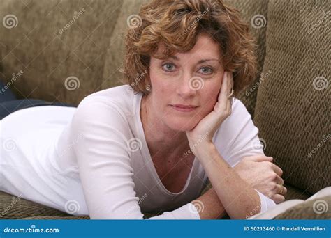 Attractive Brunette Woman Relaxing On Couch With Book Stock Photo