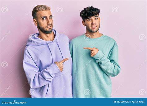 Homosexual Gay Couple Standing Together Wearing Casual Clothes Pointing Aside Worried And