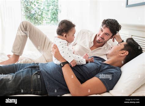 Gay Fathers Playing With Baby Son On Bed Stock Photo Alamy