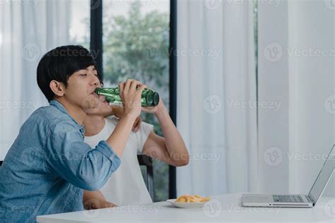 Jovem Casal Gay Bebe Cerveja Enquanto Usa O Laptop Do Computador Em Uma Casa Moderna Homens