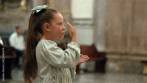 Niña hermosa rubia latina hispana rezando meditando orando con sus manos juntas hincada de