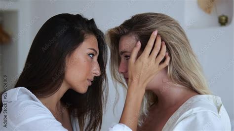 Two Sensual Lesbians Are Sitting On The Bed In Front Of Each Other The Brunette Runs Her Hand