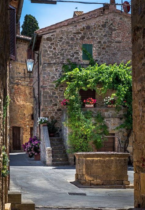 An Alley Way With Stone Buildings And Flowers Growing On The Wall