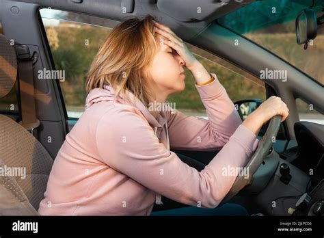 Eine junge blonde nervöse Frau sitzt hinter dem Steuer eines Linksfahrwagens und hält ihren