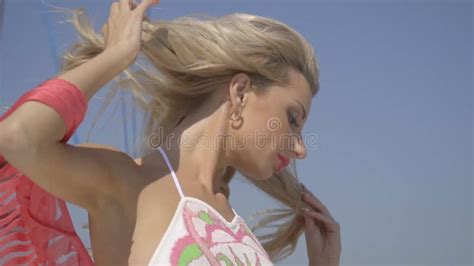 A Blonde In A Swimsuit And Shawls Straightens Her Hair Against The Blue Sky Slow Motion Shooting