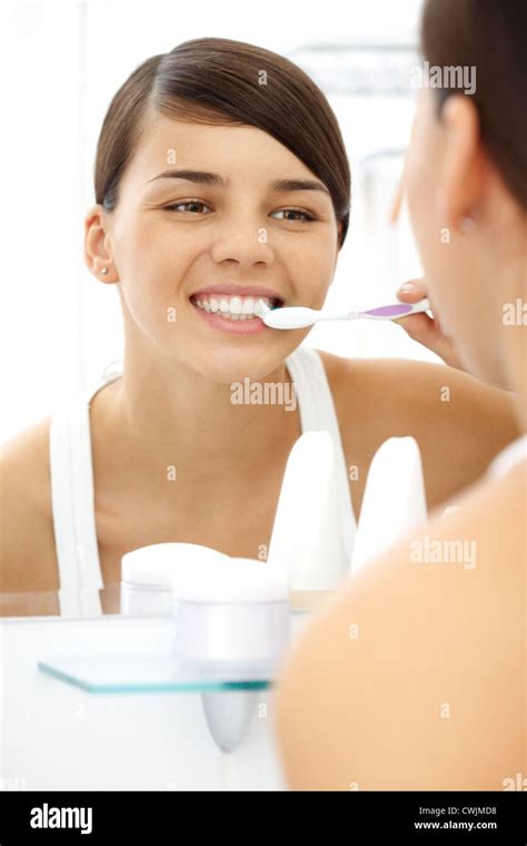 Image Of Pretty Female Brushing Her Teeth In Front Of Mirror In The