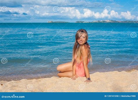 Jovem Mulher Feliz No Roupa De Banho Cor De Rosa Que Senta Se Na Praia