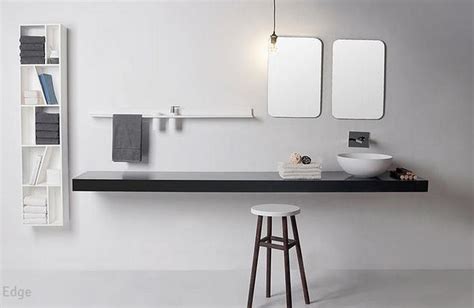 A White Bathroom With Black Counter Top And Two Mirrors On The Wall