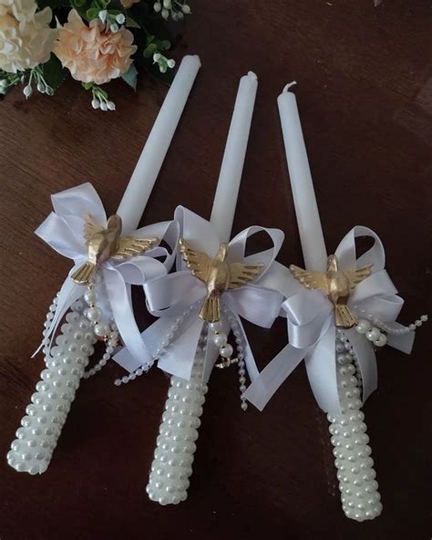 Three White Candles With Bows And Pearls On Them Sitting On A Table