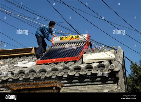 A Man Installs Solar Power Powered Hot Water Heater Tank On House Roof In Central Beijing