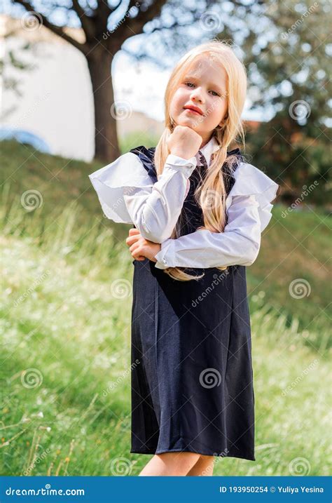 Une Petite Fille Blonde Avec Deux Queue De Cheval En Uniforme Scolaire Pose Dans Le Contexte Du