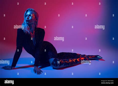 Blonde Sparkling Woman Covered In Glitter Posing In Shiny Outfit Under Colored Lights In Studio