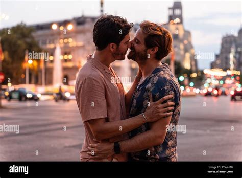 A Tender Scene Unfolds As A Gay Couple Shares A Loving Kiss In A Bustling City S Evening Glow