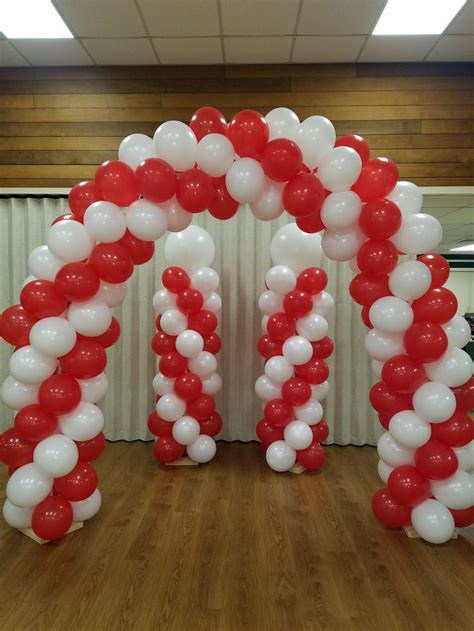 An Arch Made Out Of Red And White Balloons On A Wooden Floor In Front