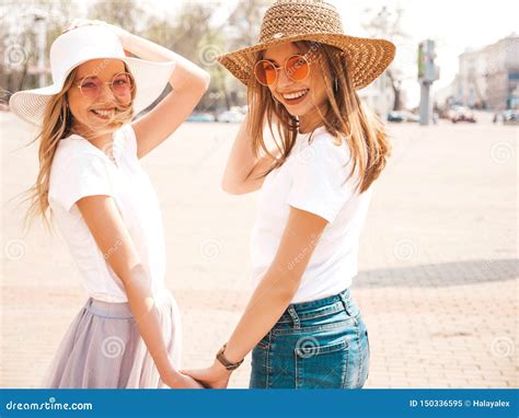 Twee Jonge Glimlachende Hipster Blonde Vrouwen In Kleren Van De De Zomer De Witte T Shirt Stock