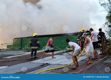 Firemen And Volunteers On Rooftop Put Out Fire Using Fire Hose During