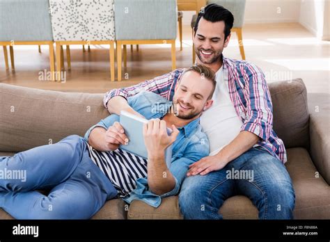 Gay Couple Relaxing On The Couch Using Tablet Stock Photo Alamy