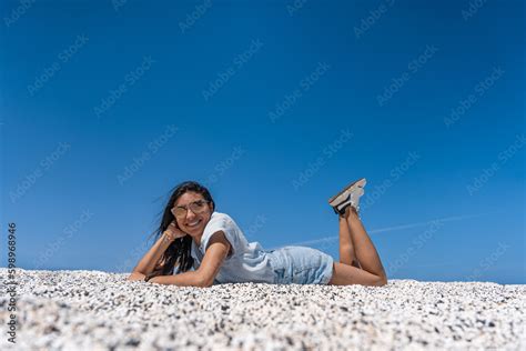 Mujer Latina Acostada Boca Abajo En Arena Blanca Con Cielo Azul De Fondo Con Una Sonrisa Y Pose