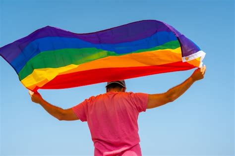 Una persona gay con la bandera lgbt en la espalda moviéndose con el viento con el cielo de fondo