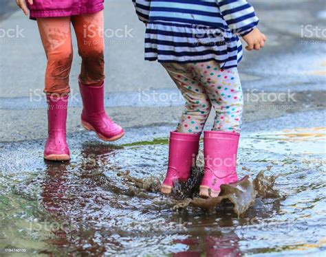 Playful Child Outdoor Jump Into Puddle In Boot After Rain Stock Photo