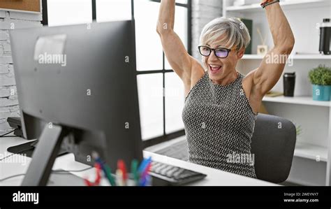 A Joyful Mature Woman With Grey Hair Celebrates Success At Her Office Workspace Stock Photo Alamy