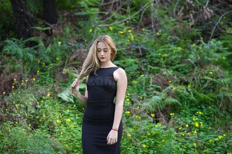 Young Beautiful Blonde Woman Dressed In Black Walks Through The Forest