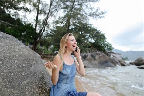 Jonge Blonde Meid Zit Op Zand In De Buurt Van Zee En Stenen Praat Met Een Smartphone En Laat