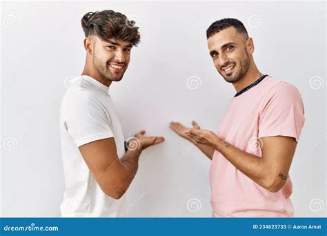 Pareja Joven Gay De Pie Sobre Un Fondo Aislado Invitando A Entrar En Natural Sonriente Con La