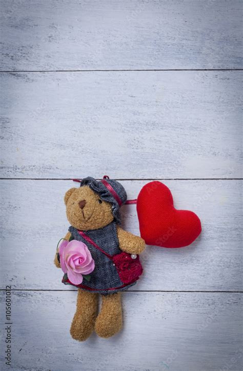 Teddy bear holding heart with space on wood background vertical style ...