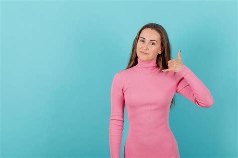 La fille blonde montre le geste de téléphone avec la main sur le fond bleu Photo Gratuite
