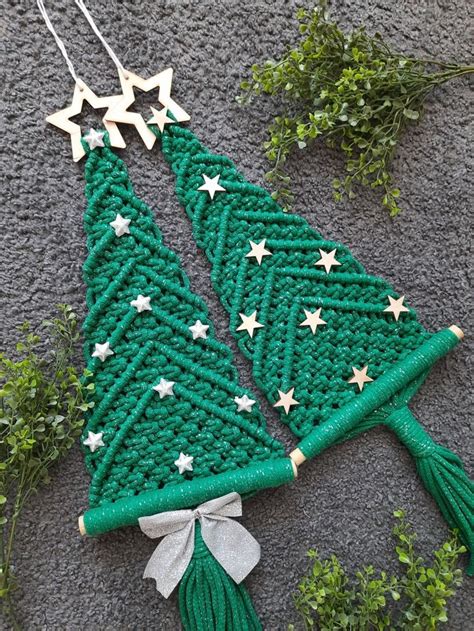 A Crocheted Christmas Tree Ornament Hanging On A Wall Next To Greenery