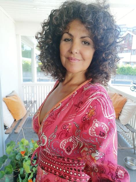 Premium Photo Portrait Of Smiling Mature Woman With Curly Hair Standing In Porch