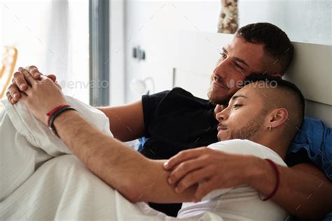 Male Gay Couple Cuddling While Relaxing In Bed Together Stock Photo By Alvarogonzalez