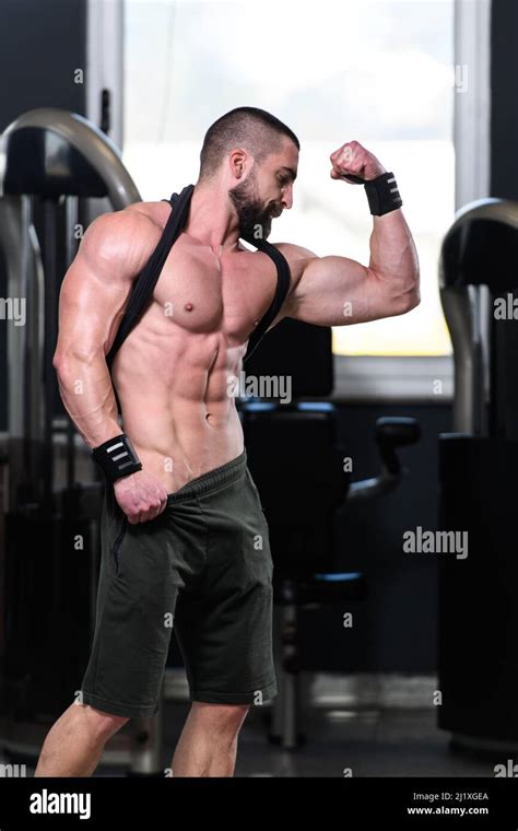 Handsome Young Man Standing Strong In The Gym And Flexing Muscles ...