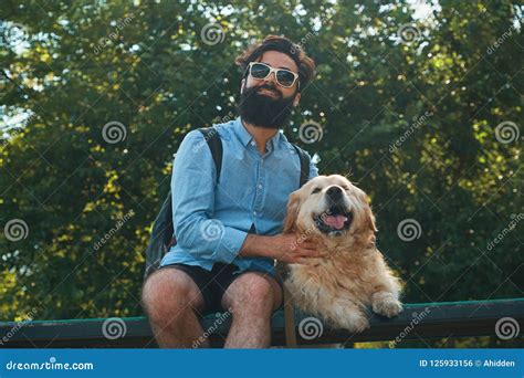 Interesting Man Sitting With His Dog On The Chair In The Park En Stock