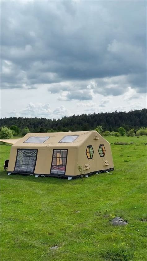 a tent in the middle of a field with windows on it's roof and grass