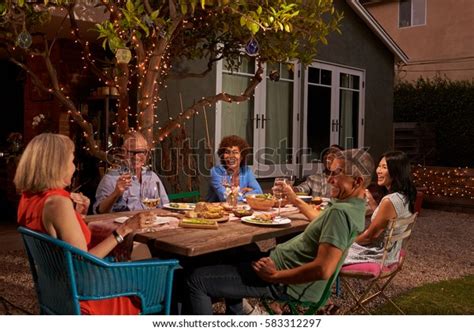 Group Of Mature Friends Enjoying Outdoor Meal In Backyard