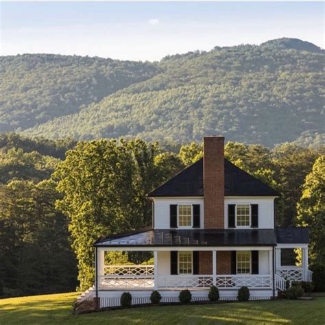 A Large White House Sitting In The Middle Of A Lush Green Field With