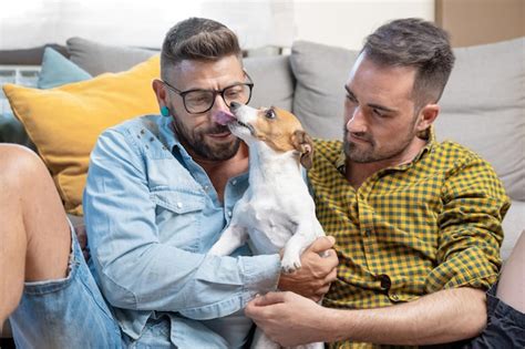 Feliz Pareja Gay Sentada En El Suelo Y Jugando Con El Perro En Casa Foto Premium