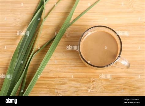 Glass Cup Of Hot Ginger Tea With Ginger Rhizome Root Sliced Isolated On Wooden Background