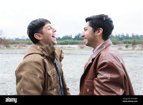 A Cheerful Gay Couple Shares A Heartwarming Laugh In A Serene Outdoor Setting Embodying Love