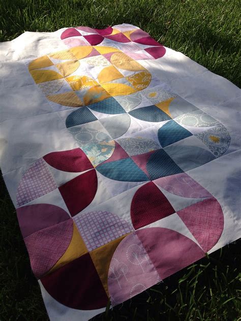 A Quilt Is Laying On The Grass In Front Of Some Green Grass And It S