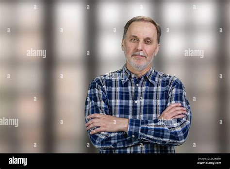 Portrait Of A Handsome Mature Man With Folded Arms Standing In Office Checkered Windows