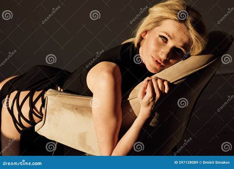 A Blonde Woman In A Black Dress Sits In A Chair In A Dark Room Stock Image Image Of Black