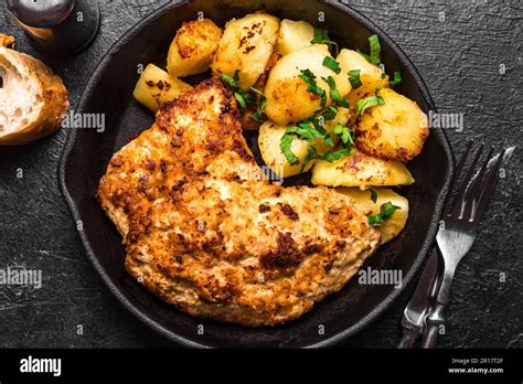 Schnitzel alemán con patatas asadas en una bandeja rústica de hierro