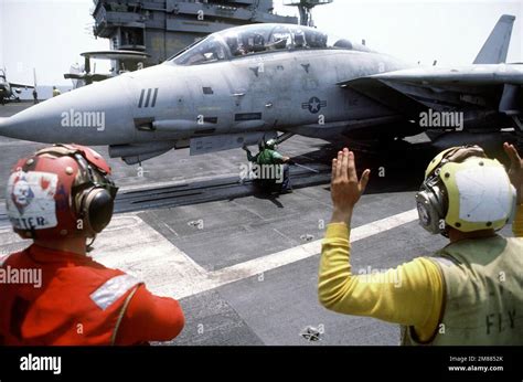 A Plane Director Signals Instructions To The Pilot Of An F 14A Tomcat