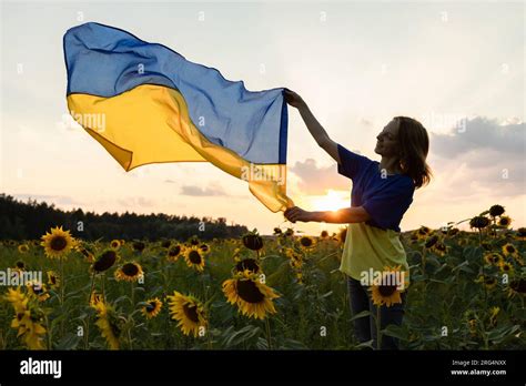 Ukrainian Flag In Hands Of Woman Standing On Blooming Field Of