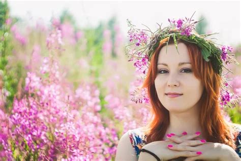 Young Beautiful Red Haired Woman With A Wreath Of Pink Wildflowers On Her Head Looks At The